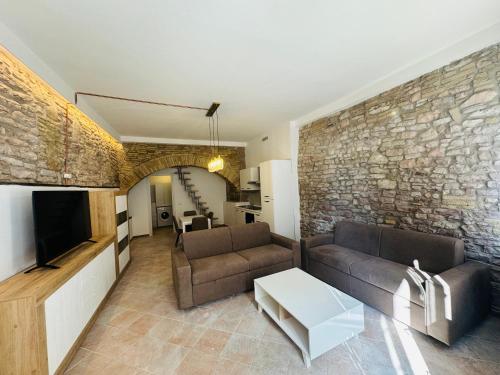 a living room with a couch and a stone wall at Giulivi Assisi Apartments in Assisi