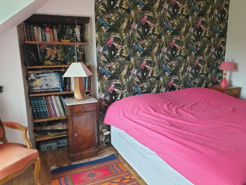 1 dormitorio con cama rosa y estante para libros en Eoz an avel, en Combourg