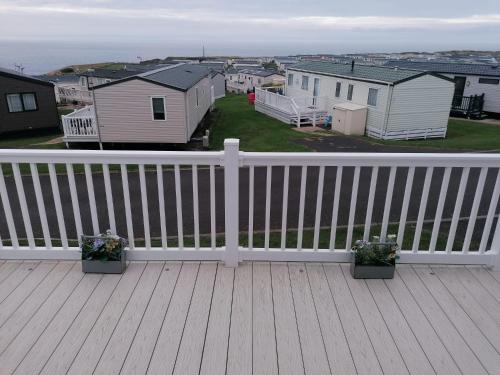 a white railing on a deck with houses at 3-Bed Lodge with SeaView-Fireplace-Garden-FreeP in Eyemouth