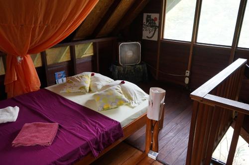 Schlafzimmer mit einem Bett mit lila Bettwäsche und Kissen in der Unterkunft Chalet at the river's edge in Dos Brazos