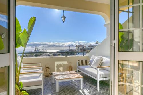 einen Balkon mit weißen Möbeln und Meerblick in der Unterkunft Por do Sol, a Home in Madeira in Ponta do Sol
