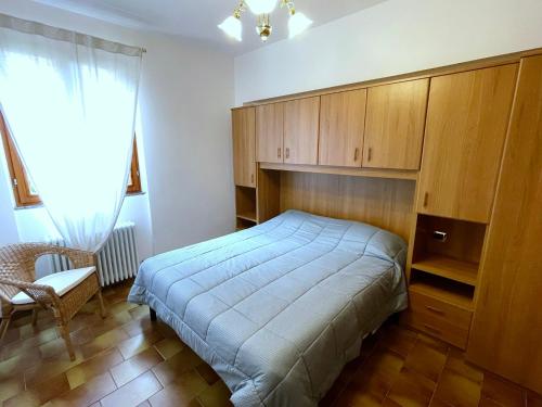 una camera con letto, armadi in legno e sedia di LovingStresa3 giardino del lago a Stresa