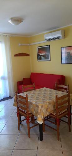 uma mesa com dois bancos e um sofá vermelho em casa vacanze Gina em San Foca