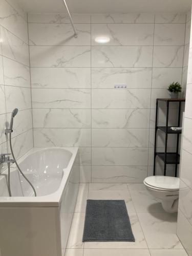 a white bathroom with a tub and a toilet at Apartman Leo in Klinča Sela