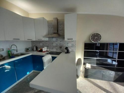 uma cozinha com armários azuis e um relógio na parede em Bluesky apartment em Giardini Naxos
