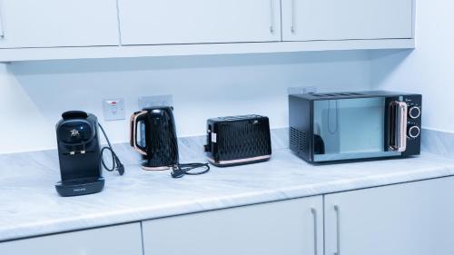 a counter with a microwave and other appliances on it at 1BR Sleeps 4, 3 mins from City centre & Local Gems in Burton upon Trent