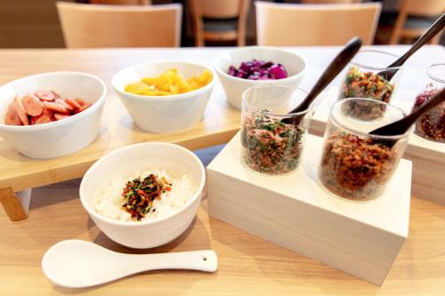 a table topped with bowls of different types of food at Business Inn Norte in Sapporo