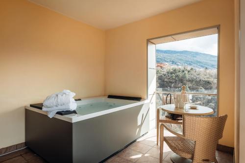 a bath tub in a room with a table and a window at Hotel Villa Madruzzo in Trento