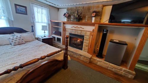Schlafzimmer mit einem Bett, einem Kamin und einem TV in der Unterkunft The Miners’ Lodge in Northern Cambria