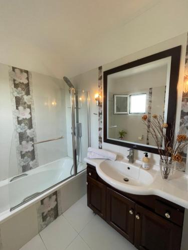 bagno con lavandino, vasca e specchio di Olgas Luxury Villa, Corfu Greece a Evropoúloi