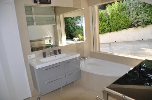baño con lavabo, bañera y ventana en Villa de standing chambres climatisées avec piscine et jardin privatifs, en Biot