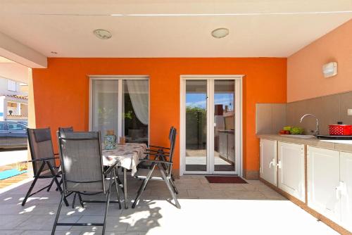 a kitchen with an orange wall and a table and chairs at Ferienhaus mit Privatpool für 6 Personen ca 80 qm in Barbariga, Istrien Istrische Riviera in Barbariga