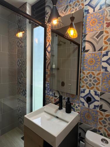 ein Badezimmer mit einem Waschbecken, einem Spiegel und einem WC in der Unterkunft Villa Luz in Villavicencio
