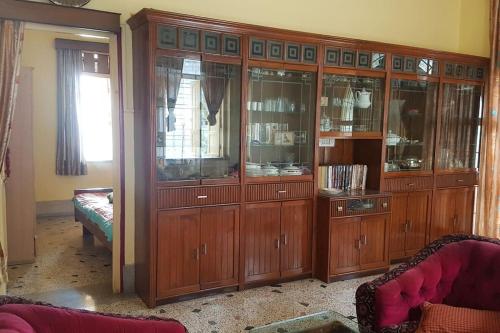 un gran armario de madera con puertas de cristal en la sala de estar. en Premium Apartment, Kolkata Airport, en kolkata