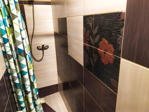 y baño con ducha y pared de azulejos florales. en Noclegi Relax, en Ruciane-Nida