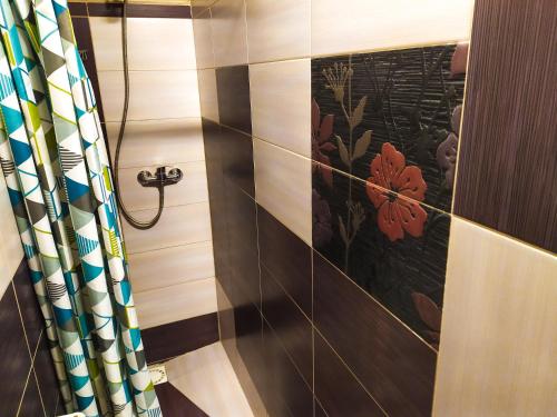 a bathroom with a shower with a floral tile wall at Noclegi Relax in Ruciane-Nida