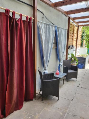 a patio with red curtains and a table and chairs at Appartement Purzel in Mauerbach