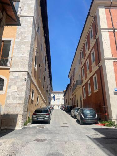 a street with cars parked on the sides of buildings at Casa Renzo in LʼAquila