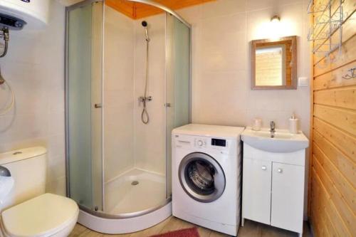 La salle de bains est pourvue d'une douche et d'un lave-linge. dans l'établissement Domki całoroczne NEMO, à Ustronie Morskie