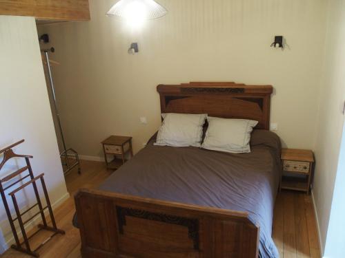 1 dormitorio con 1 cama grande de madera y 2 almohadas en Gît' de Pom', en Saint-Romain-de-Lerps
