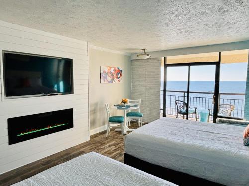 a bedroom with a fireplace and a tv and a balcony at Sea La Vie Oceanfront Studio in Myrtle Beach