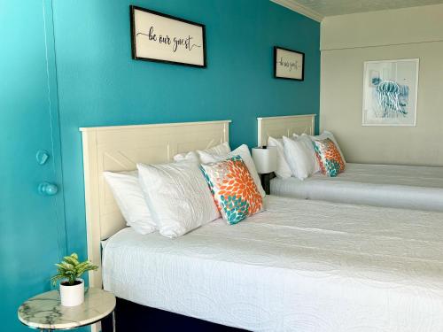 two beds in a room with blue walls at Sea La Vie Oceanfront Studio in Myrtle Beach
