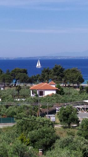 a white sail boat in the water with a house at Nikitihouse Apartments 2 in Nikiti