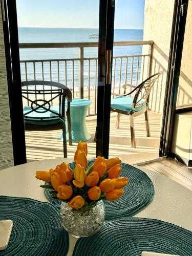 a vase of flowers on a table with a view of the beach at Sea La Vie Oceanfront Studio in Myrtle Beach