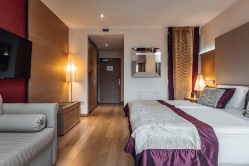 a hotel room with a large bed and a couch at Hotel Villa Madruzzo in Trento