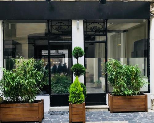 uma frente de loja com dois vasos de plantas em frente em Parisian Studios Louvre -Vendôme em Paris