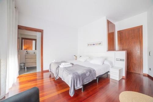 a bedroom with a large white bed and a wooden floor at Mazi Apartments Colón in Vic
