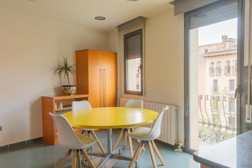 comedor con mesa amarilla y sillas blancas en Mazi Apartments Colón, en Vic