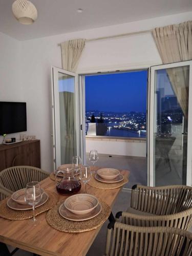 a wooden table with chairs and plates and wine glasses at Villa Filothea with Jacuzzi and sea view in Spartýlas
