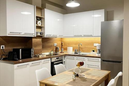 a kitchen with white cabinets and a wooden table with chairs at Central Cozy Apartment in Tríkala