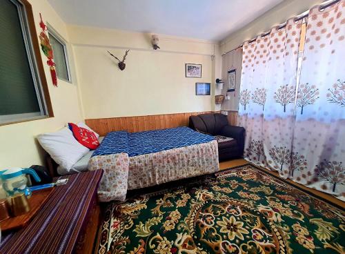 a small bedroom with a bed and a couch at Paul's stay in Darjeeling