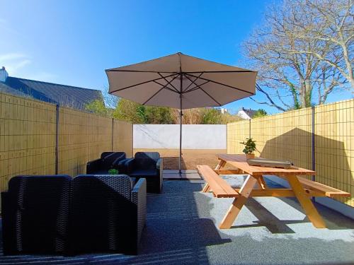 einen Picknicktisch und einen Regenschirm im Hinterhof in der Unterkunft BZHouse - Terrasse - Climatisation - Wifi in Belz