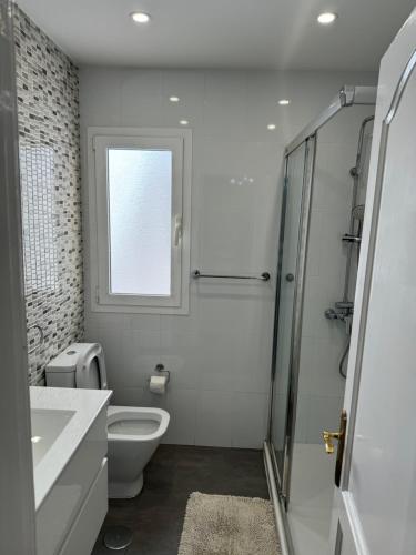 a white bathroom with a toilet and a window at Apartamento Corralejo in Corralejo