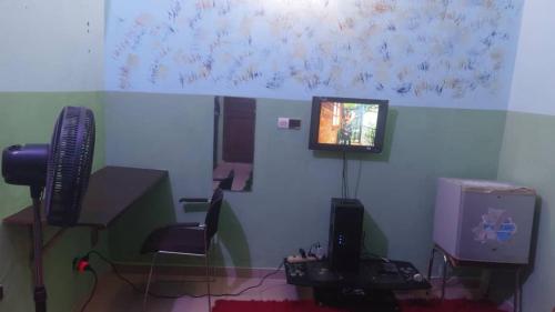 um escritório com um computador e uma televisão na parede em NEW LIGHT em Cotonou
