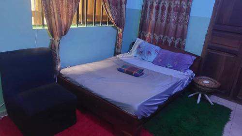um pequeno quarto com uma cama e uma cadeira em NEW LIGHT em Cotonou