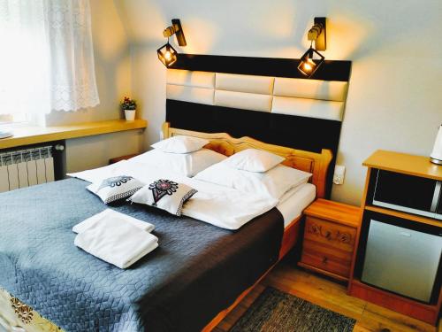 a bedroom with a bed with white pillows and a television at Pokoje Gościnne " W zasięgu Tatr" in Kościelisko