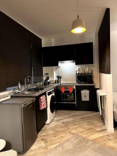 eine Küche mit schwarzen Schränken und Edelstahlgeräten in der Unterkunft High-quality flat near city in Brüssel