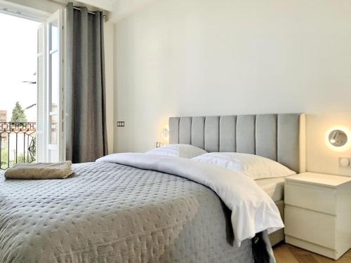 une chambre blanche avec un grand lit et une fenêtre dans l'établissement Bright, newly renovated apartment, à Nice