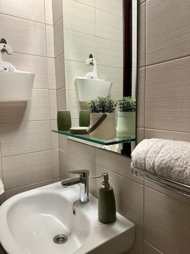 ein Bad mit einem Waschbecken und einem Spiegel in der Unterkunft Eleni's studio near the airport in Iraklio