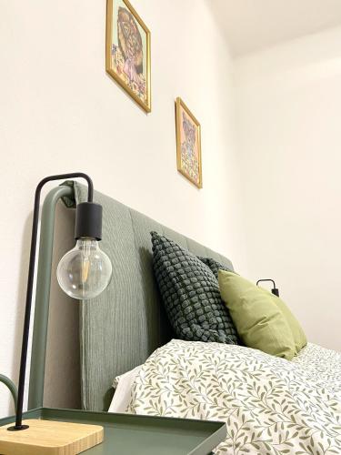 a bed with a green headboard and a lamp at Casa Ganza in Pisa