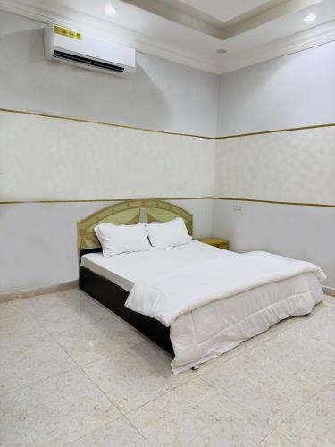 um quarto com uma cama com lençóis brancos e almofadas em FIG SHADES مزرعة ظلال التين em Ţīwī