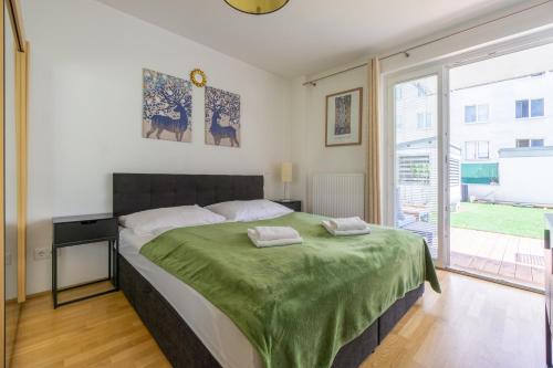 Apartment with garden close to Stadthalle, Westbahnhof في فيينا: غرفة نوم بسرير كبير مع بطانية خضراء