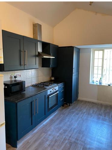 a kitchen with blue cabinets and a stove top oven at Room in CV1 Fargo Village Room with private bathroom in Parkside