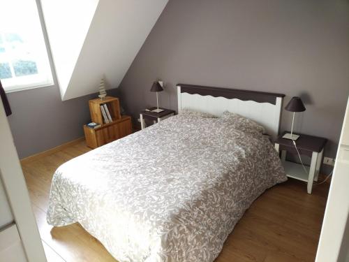 une chambre avec un lit avec une couette blanche dans l'établissement Maison avec piscine et terrasse proche plage - FR-1-418-254, à Locmaria