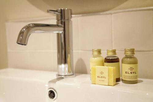 a sink with two bottles of essential oils next to a faucet at Pass the Keys Apartment 3 Old Conservative Club in Historic Town in Caernarfon