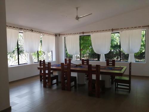 a dining room with a table and chairs and windows at Malaica in Kilifi
